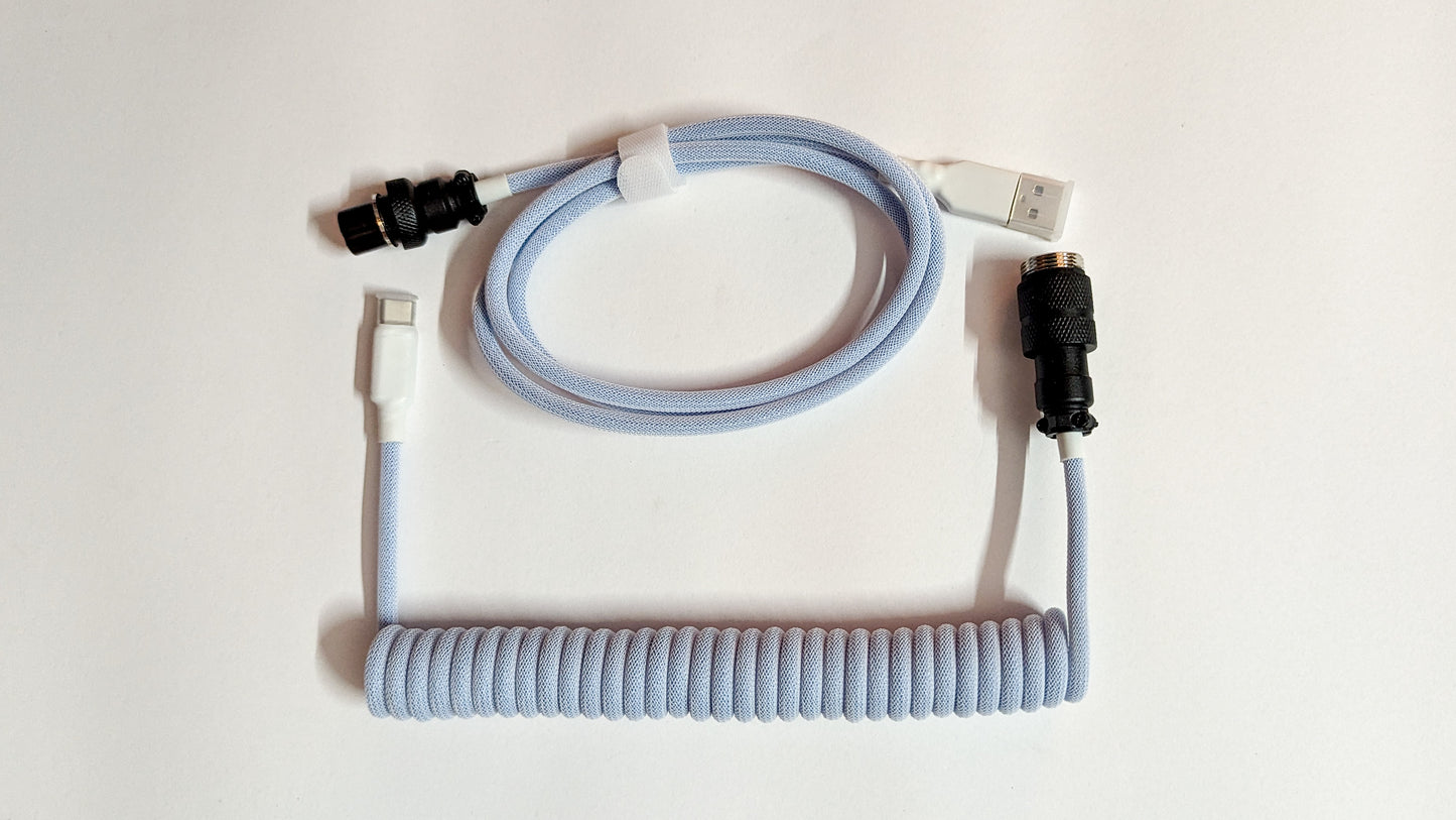 A coiled keyboard cable with a blue connector on one end and a USB-C connector on the other. The cable is blue and has a braided design.