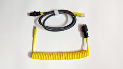 A coiled keyboard cable with yellow connectors on both ends. The cable is yellow and has a braided design.